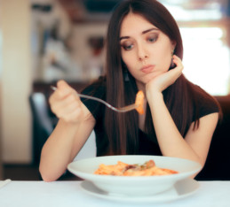 pensive woman staring at pasta dish wondering "do I have a healthy relationship with food?"