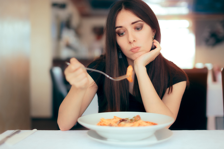 pensive woman staring at pasta dish wondering "do I have a healthy relationship with food?"